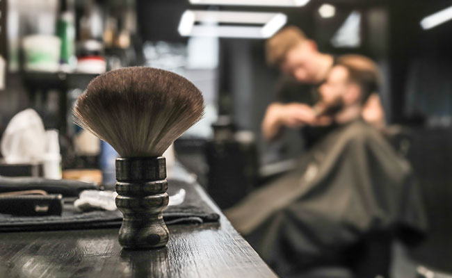 Close focus on barber brush with man getting hair cut out of focus in background